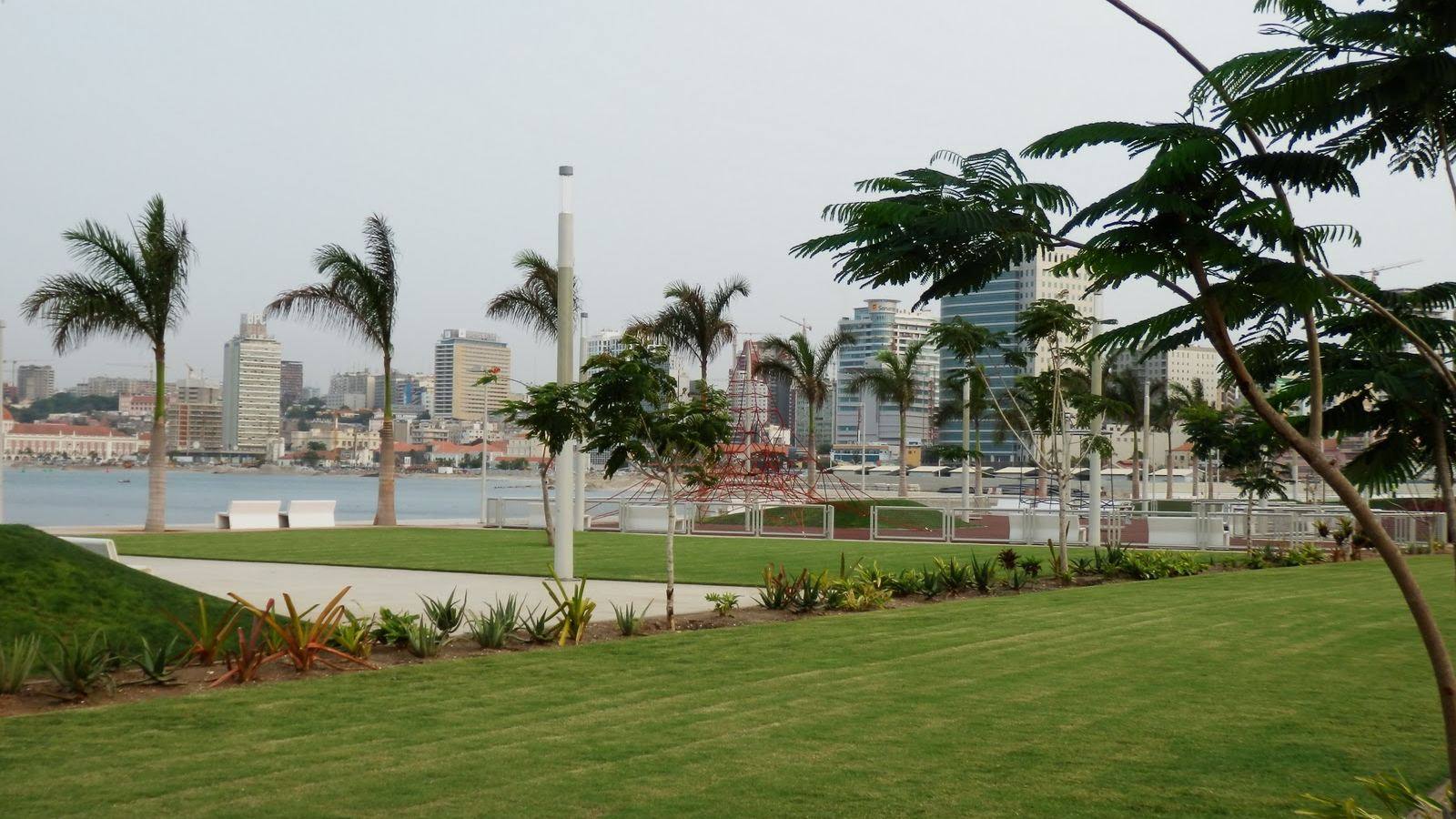 Espaço verde tratado na Marginal de Luanda, com palmeiras e a cidade ao fundo